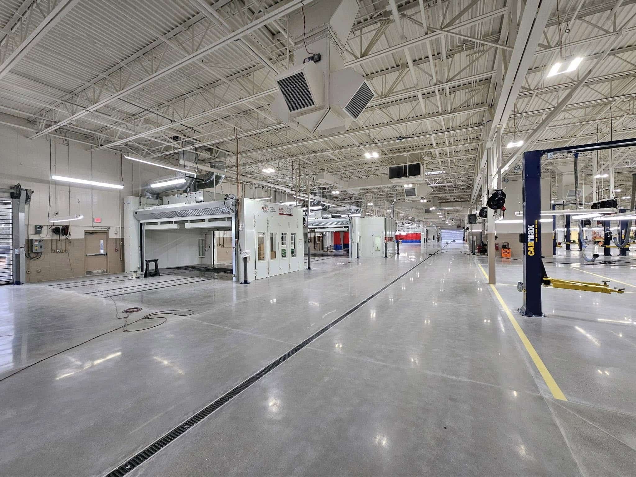 Spacious modern industrial facility with polished floors, high ceilings, exposed beams, hanging lights, and organized workstations.