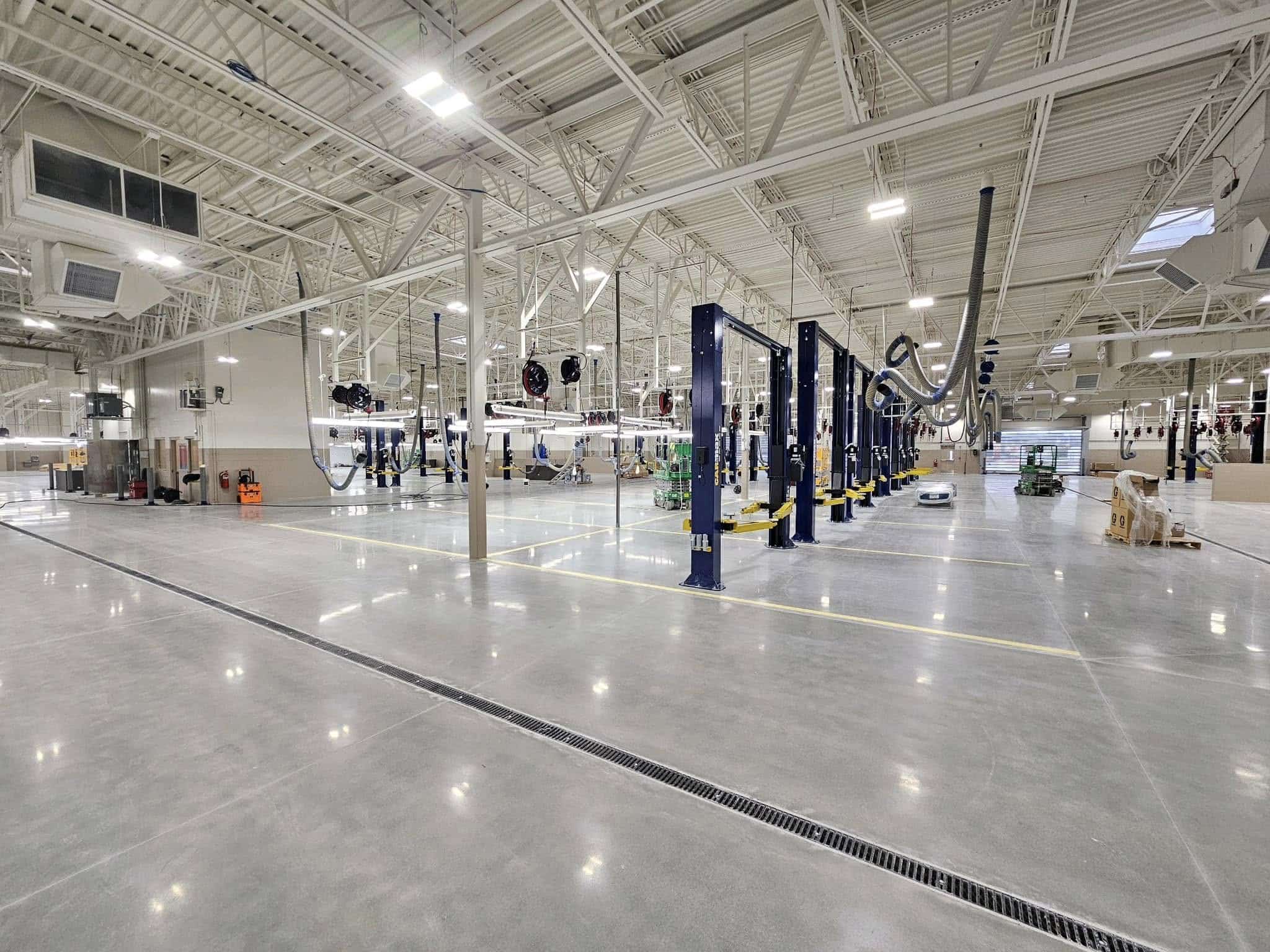 A spacious, modern industrial facility with high ceilings, bright lights, multiple workstations, and automotive lifts; clean and organized.